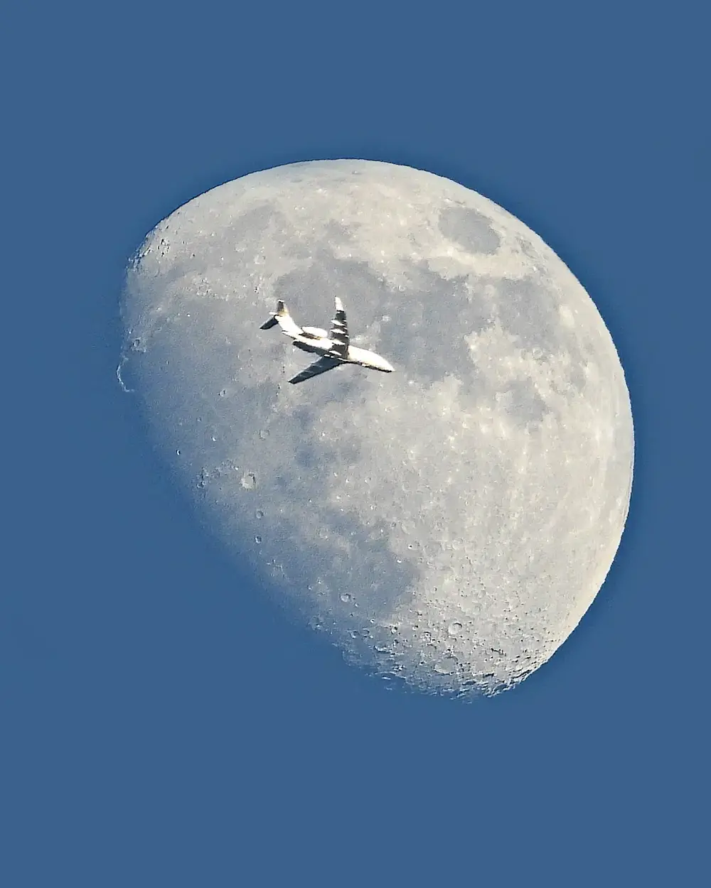 A photo of a plane intersecting the Moon, taken in York, Maine.
