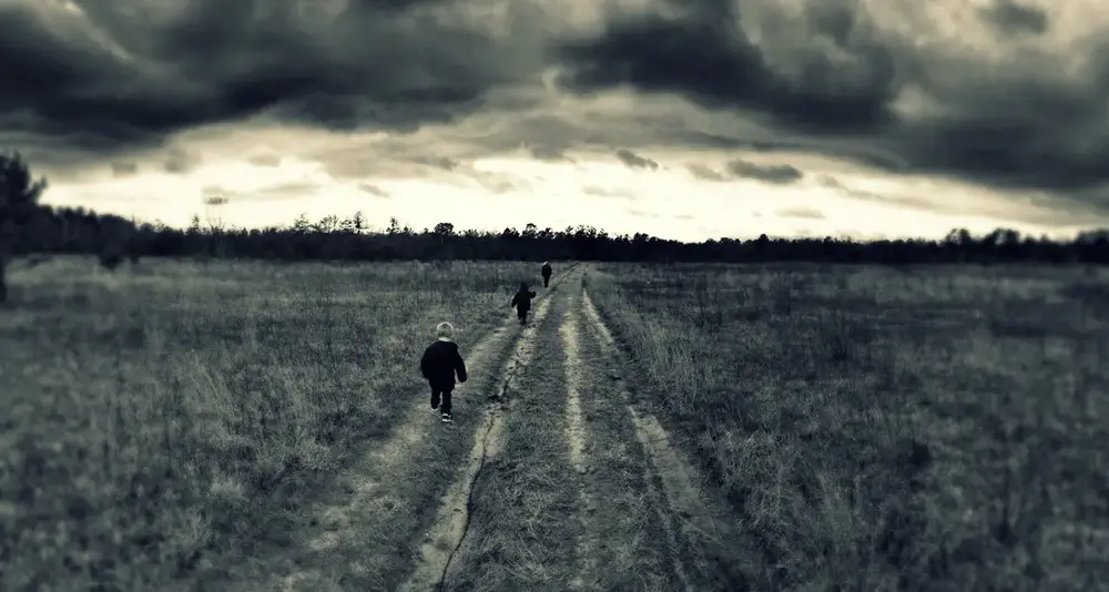 A photo of 3 people walking under stormy skies, Kennebunk Pine Barrens, Kennebunk, Maine.